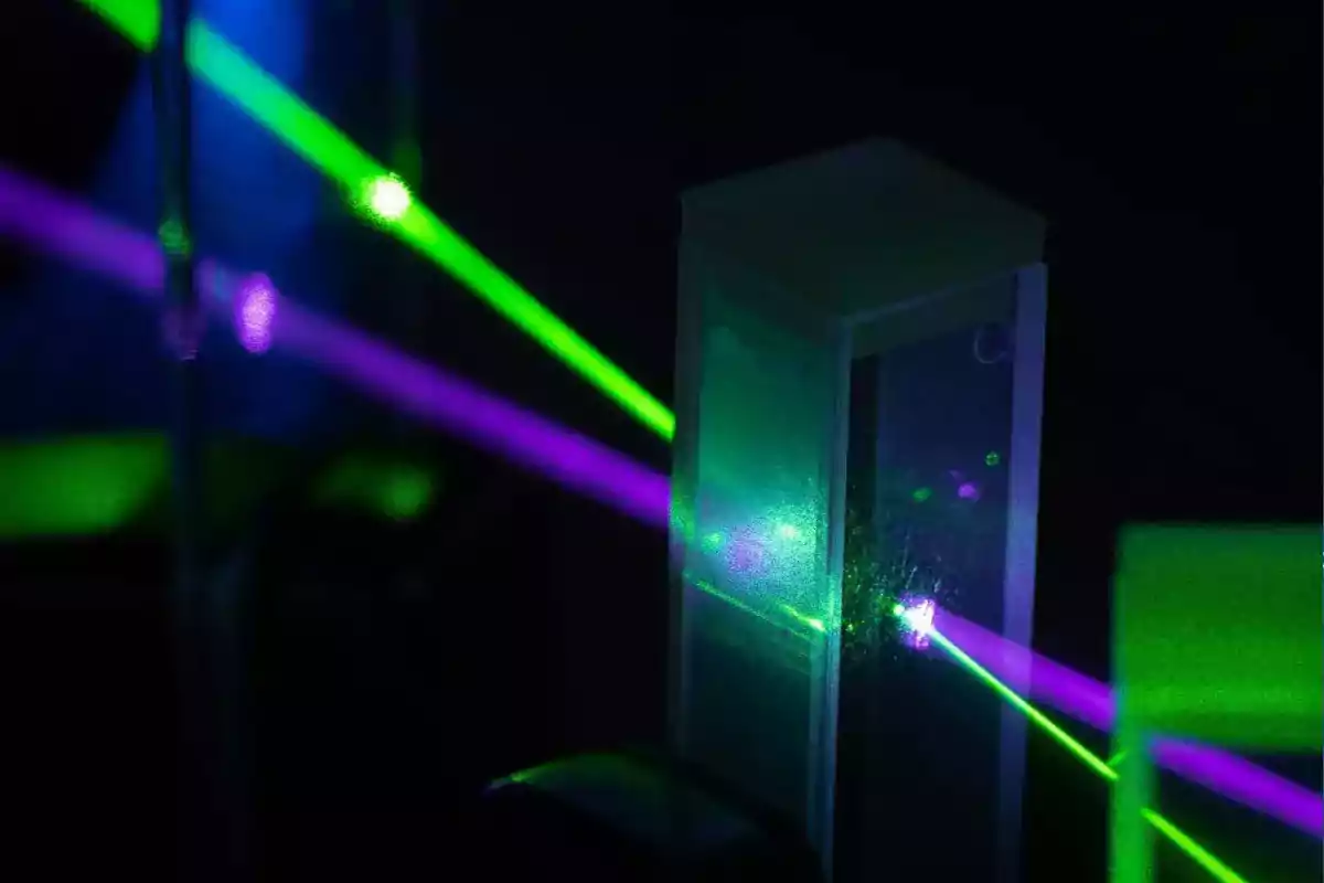 Green and purple laser beams passing through a transparent prism on a dark background Green and purple laser beams passing through a transparent prism on a dark background