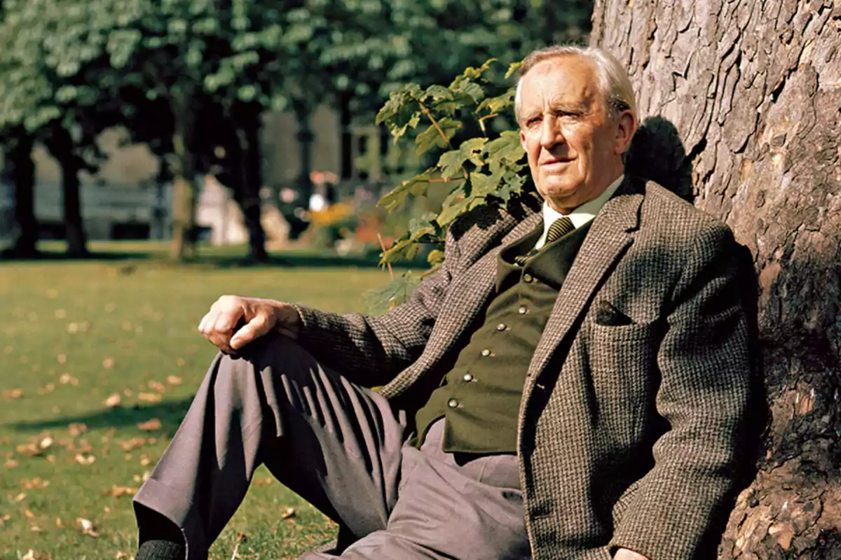 Older man sitting under a tree in a park with grass and trees in the background Older man sitting under a tree in a park with grass and trees in the background
