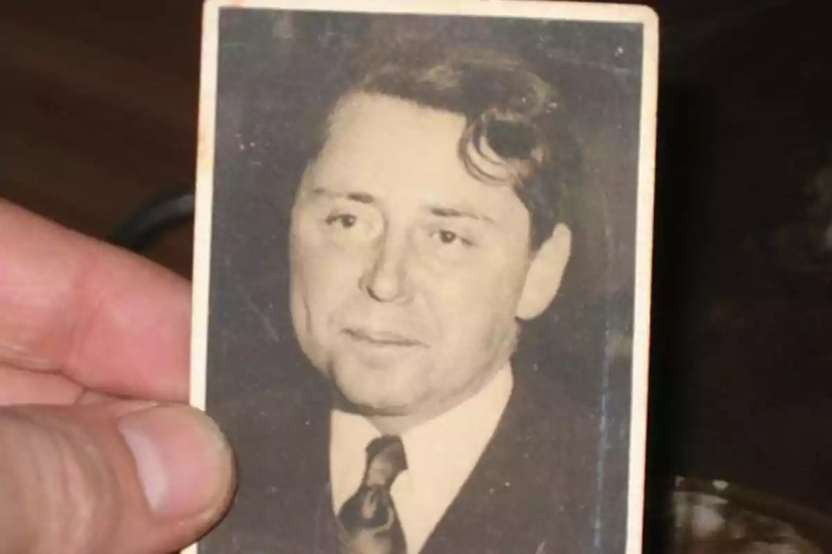 Old black-and-white photograph of a man in a suit and tie held by a hand Old black-and-white photograph of a man in a suit and tie held by a hand