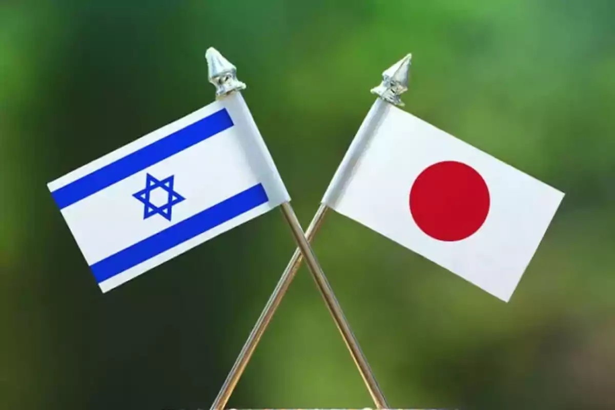 Dos banderas pequeñas de Israel y Japón cruzadas sobre un fondo verde difuminado Dos banderas pequeñas de Israel y Japón cruzadas sobre un fondo verde difuminado