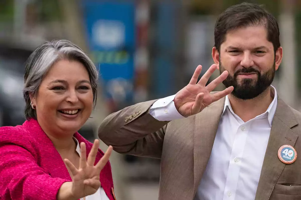 Dos personas sonríen y levantan la mano mostrando cuatro dedos cada una Dos personas sonríen y levantan la mano mostrando cuatro dedos cada una