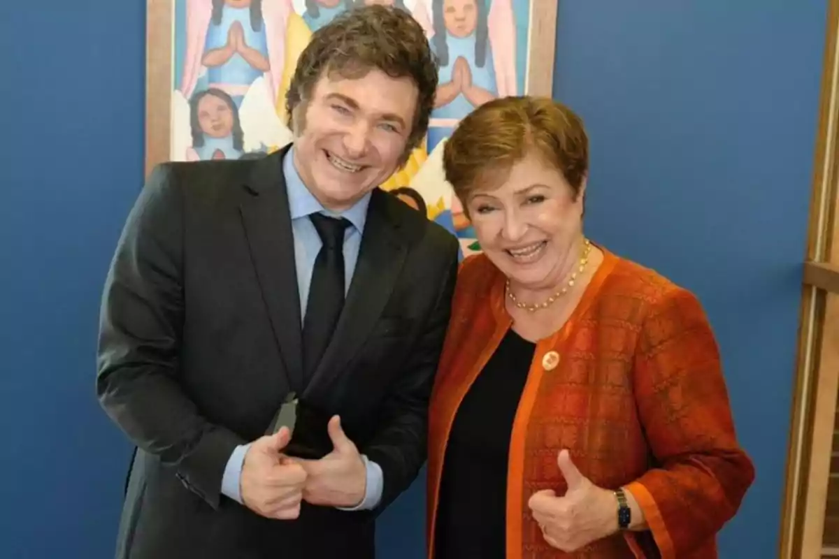 Dos personas sonríen y posan juntas haciendo el gesto de pulgar arriba frente a una pared azul y una pintura colorida. Dos personas sonríen y posan juntas haciendo el gesto de pulgar arriba frente a una pared azul y una pintura colorida.