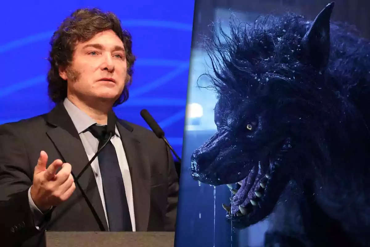 Un hombre de cabello rizado y traje oscuro está hablando frente a un micrófono, junto a la imagen de un lobo feroz con colmillos expuestos y pelaje mojado