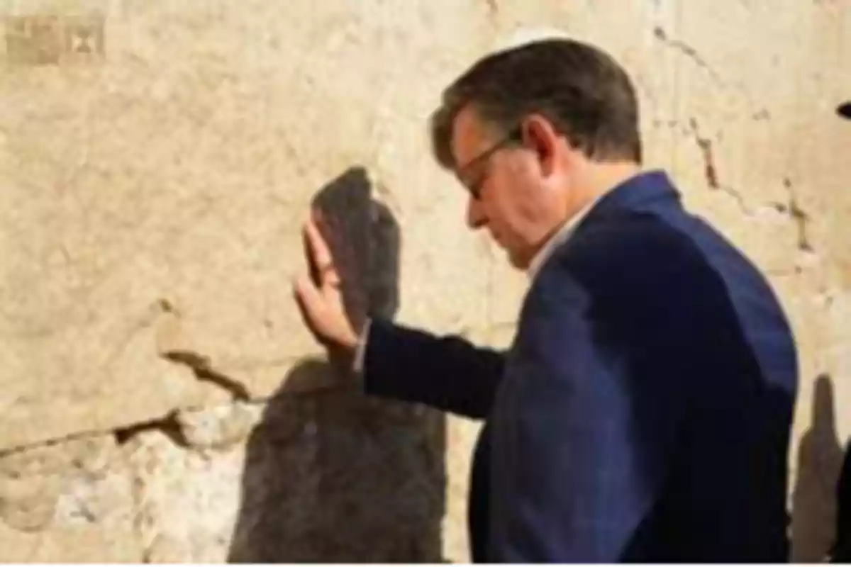 Man with glasses and kippah touching an ancient wall with his right hand Man with glasses and kippah touching an ancient wall with his right hand