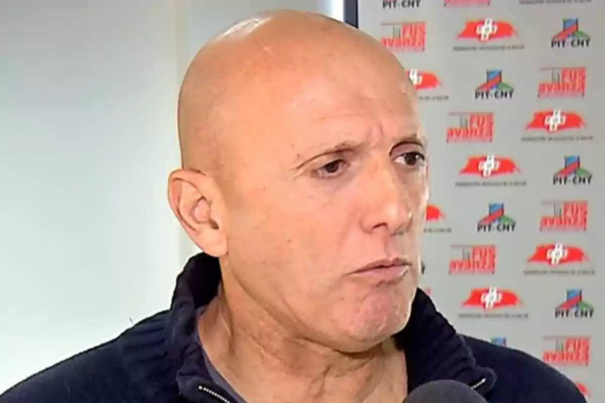 Hombre calvo hablando frente a un fondo con logotipos de la Federación Uruguaya de la Salud y PIT-CNT