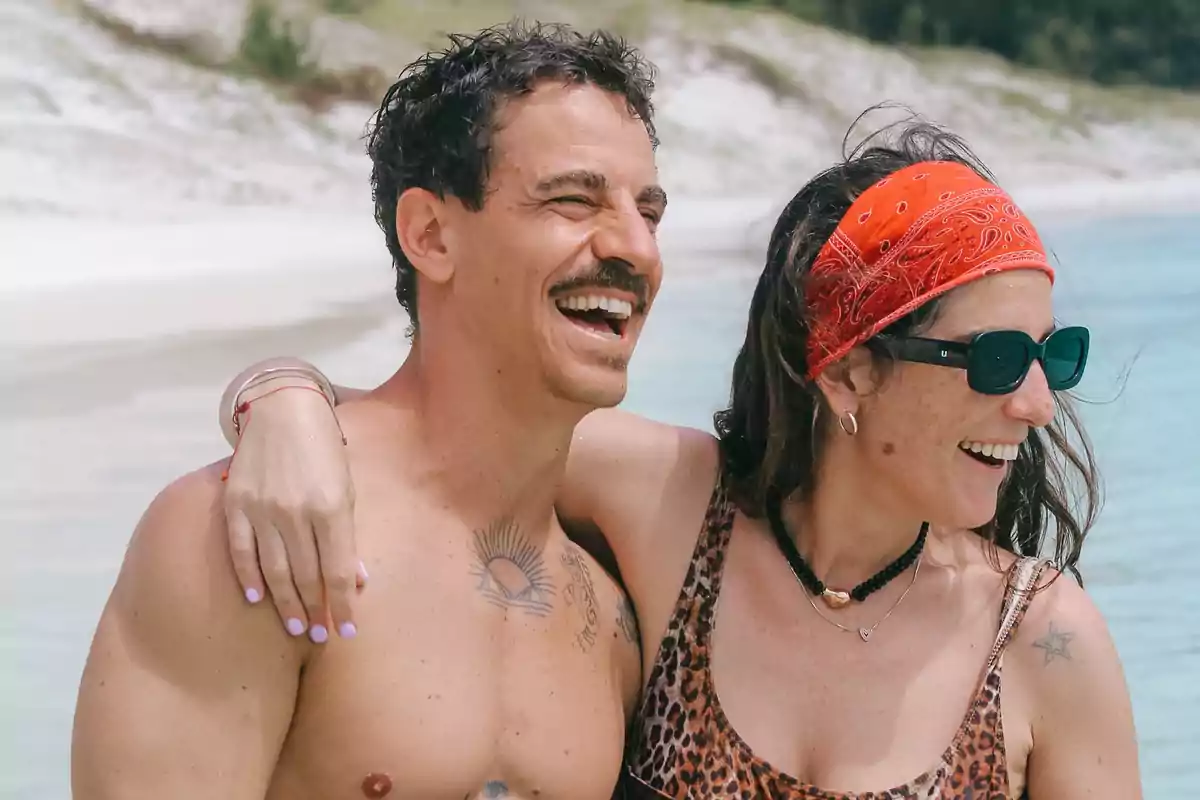Pareja sonriente disfrutando de un día en la playa con el mar de fondo