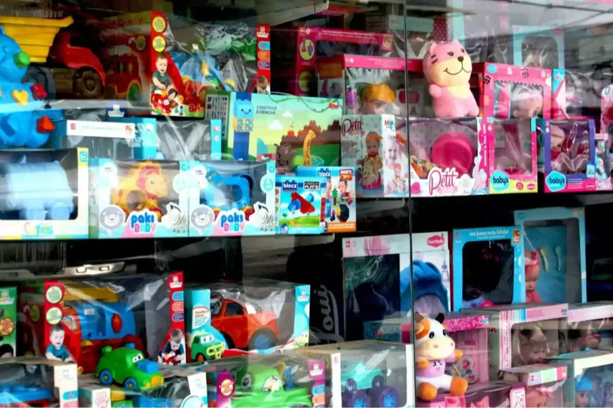Escaparate de tienda con juguetes variados como peluches, autos de juguete, muñecas y juegos de construcción en cajas de colores llamativos Escaparate de tienda con juguetes variados como peluches, autos de juguete, muñecas y juegos de construcción en cajas de colores llamativos