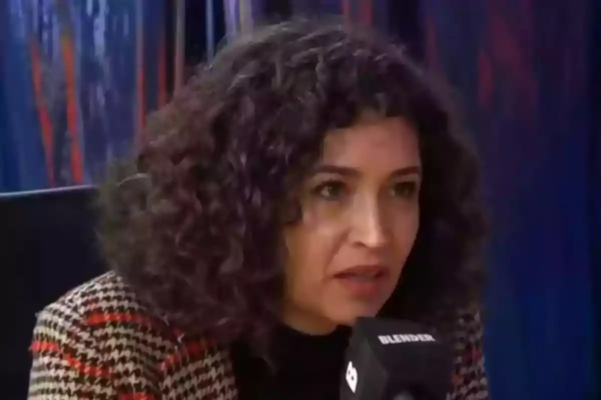 Mujer de cabello rizado hablando frente a un micrófono en un estudio de grabación Mujer de cabello rizado hablando frente a un micrófono en un estudio de grabación