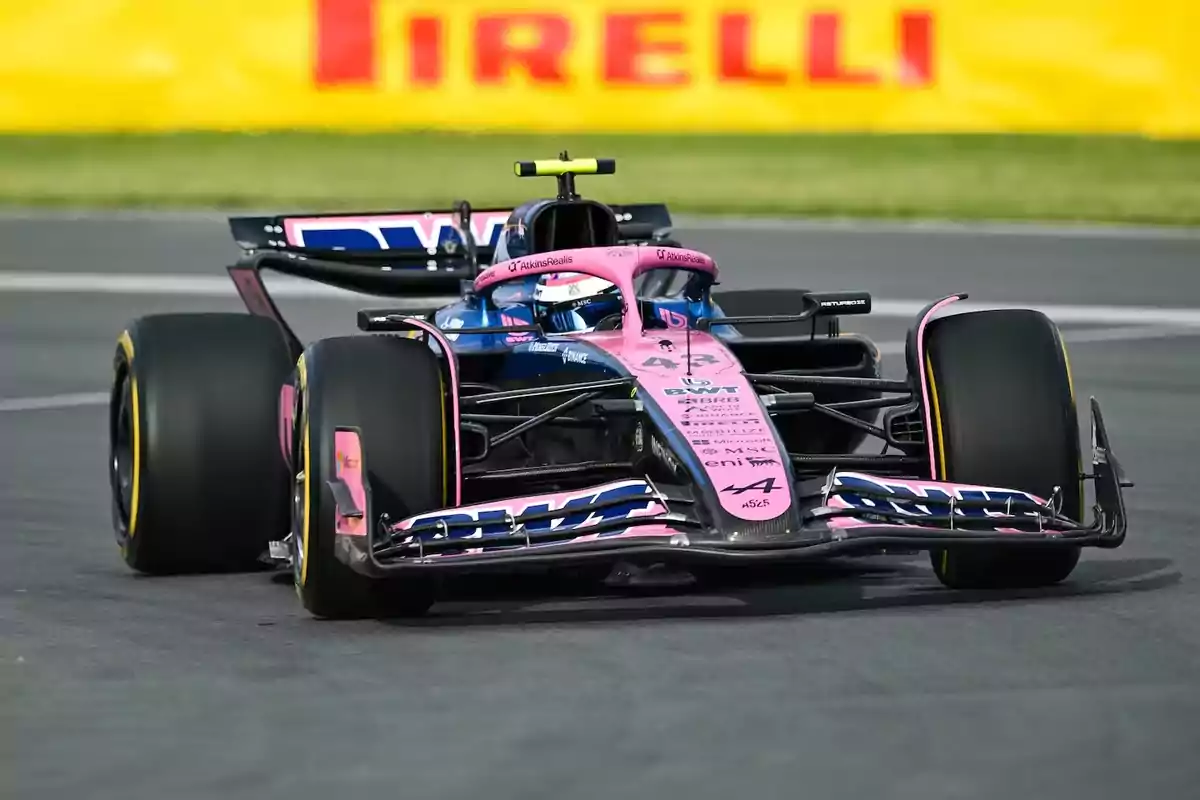 Pink and blue Formula 1 car driving on a racetrack with a Pirelli advertisement in the background Pink and blue Formula 1 car driving on a racetrack with a Pirelli advertisement in the background