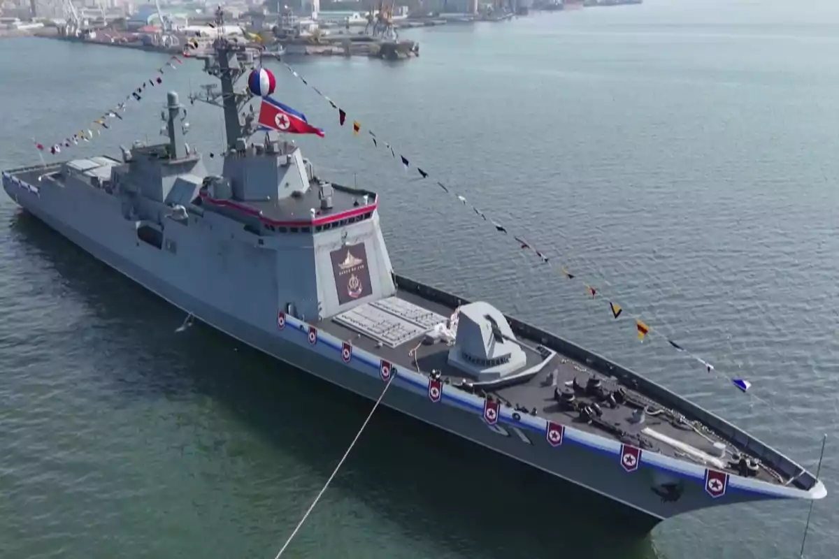 Buque de guerra gris decorado con banderas y una bandera de Corea del Norte atracado en un puerto Buque de guerra gris decorado con banderas y una bandera de Corea del Norte atracado en un puerto