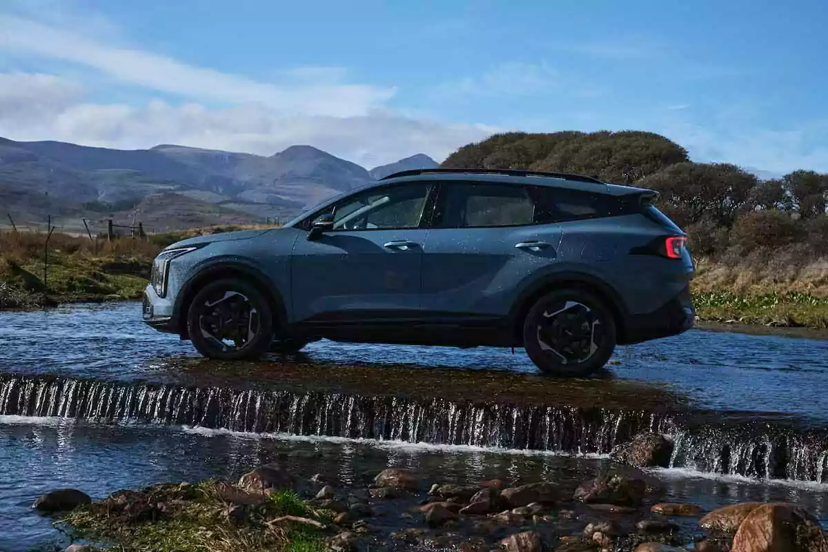 Blue SUV crossing a shallow stream in a natural setting with mountains in the background Blue SUV crossing a shallow stream in a natural setting with mountains in the background