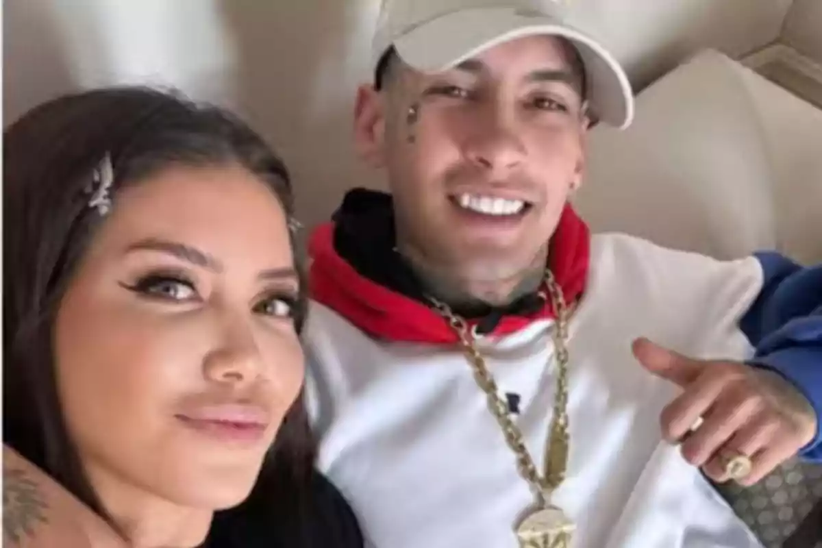 A young couple smiles while posing for a selfie in an indoor setting.