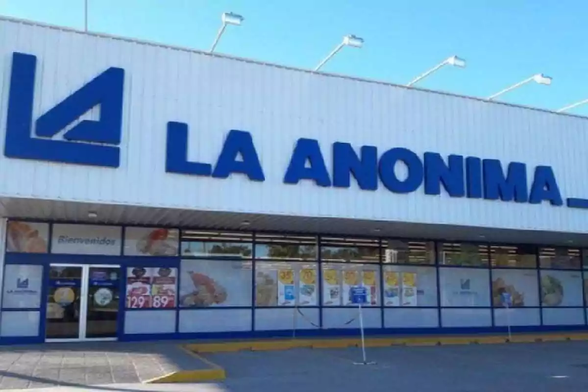Fachada de un supermercado La Anónima con el logo y el nombre en letras grandes azules Fachada de un supermercado La Anónima con el logo y el nombre en letras grandes azules