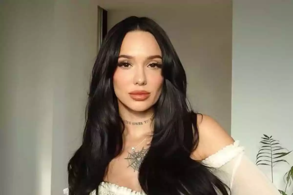 Mujer de cabello largo y oscuro con maquillaje natural y vestido claro posando en un interior iluminado Mujer de cabello largo y oscuro con maquillaje natural y vestido claro posando en un interior iluminado