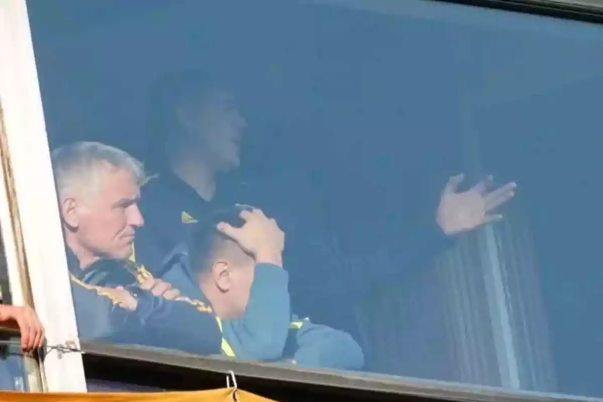 Three people are looking through a window; one of them appears frustrated with their hand on their head, and another gestures with their hand as they talk to each other. Three people are looking through a window; one of them appears frustrated with their hand on their head, and another gestures with their hand as they talk to each other.