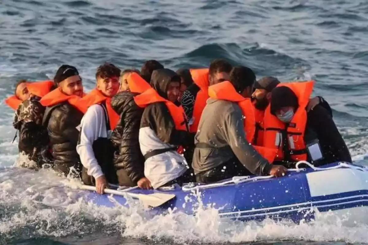 Un grupo de personas con chalecos salvavidas naranjas viaja en una balsa inflable sobre el mar Un grupo de personas con chalecos salvavidas naranjas viaja en una balsa inflable sobre el mar