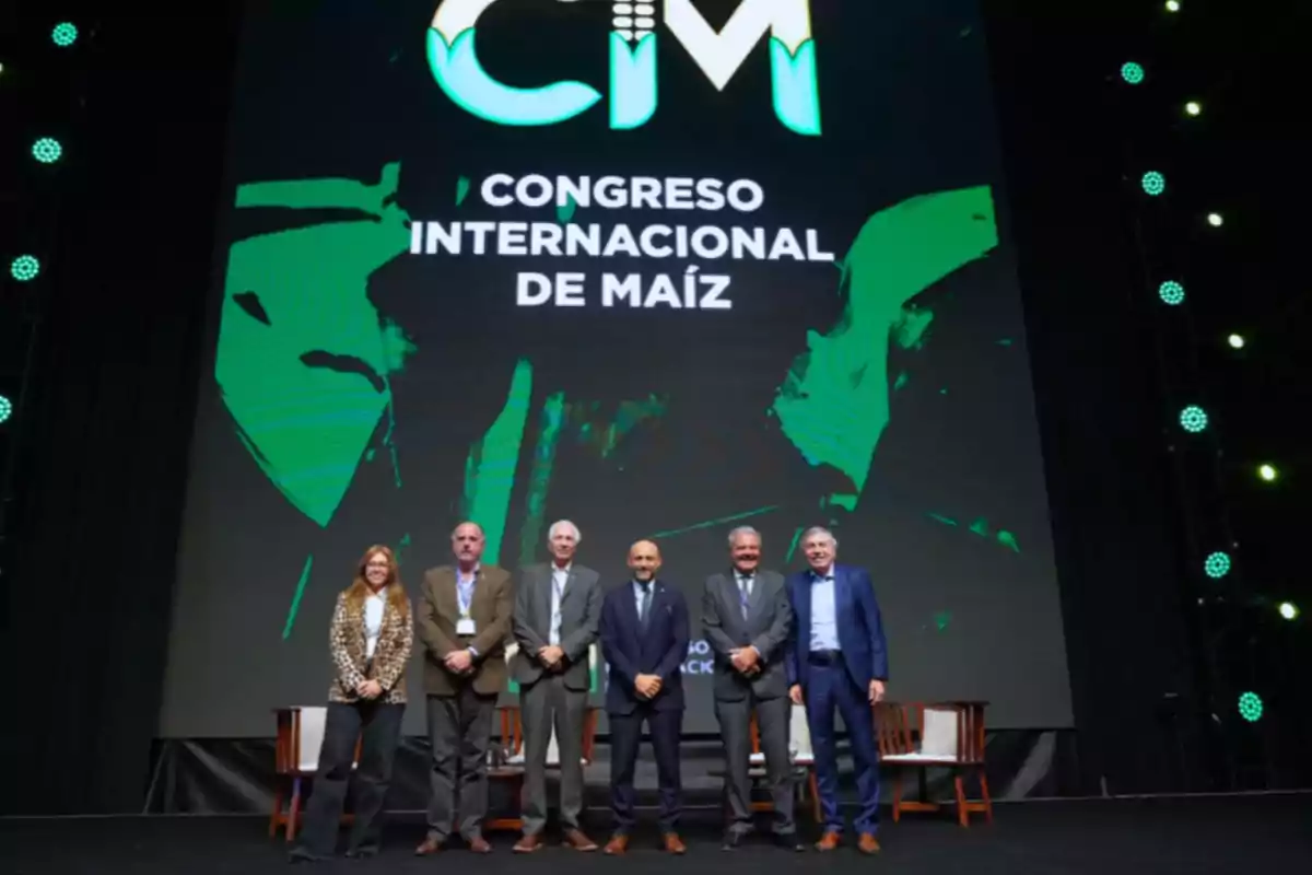 Six people pose on stage in front of a large screen displaying the text International Corn Congress.