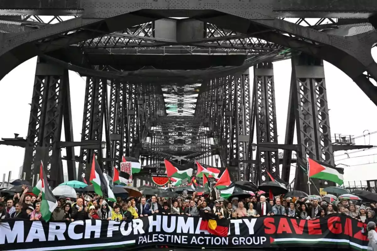 Mass demonstration on a metal-structured bridge with people holding Palestinian flags and a banner that reads March for Humanity Save Gaza Mass demonstration on a metal-structured bridge with people holding Palestinian flags and a banner that reads March for Humanity Save Gaza