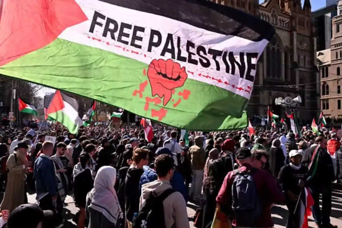 Manifestación multitudinaria con una gran bandera que dice Free Palestine ondeando sobre la multitud en una ciudad