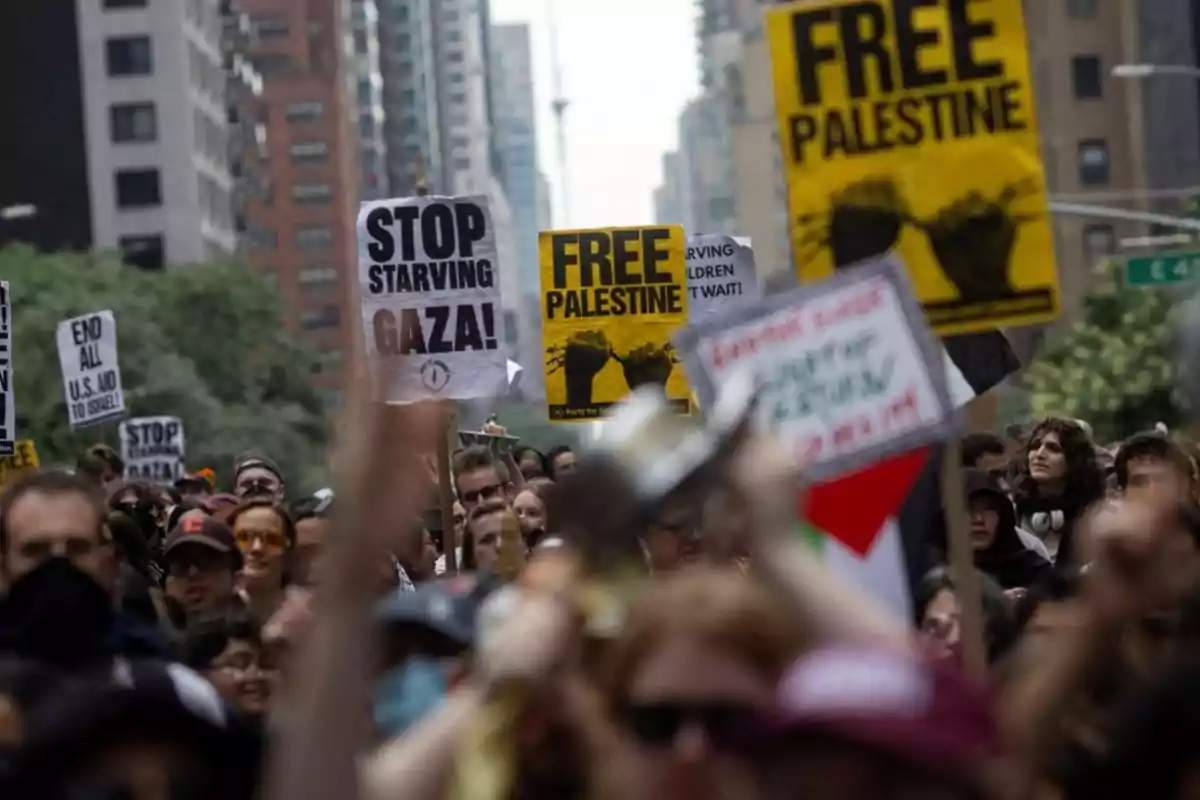 Manifestación en una ciudad con personas sosteniendo pancartas que piden el fin del apoyo a Israel y la liberación de Palestina