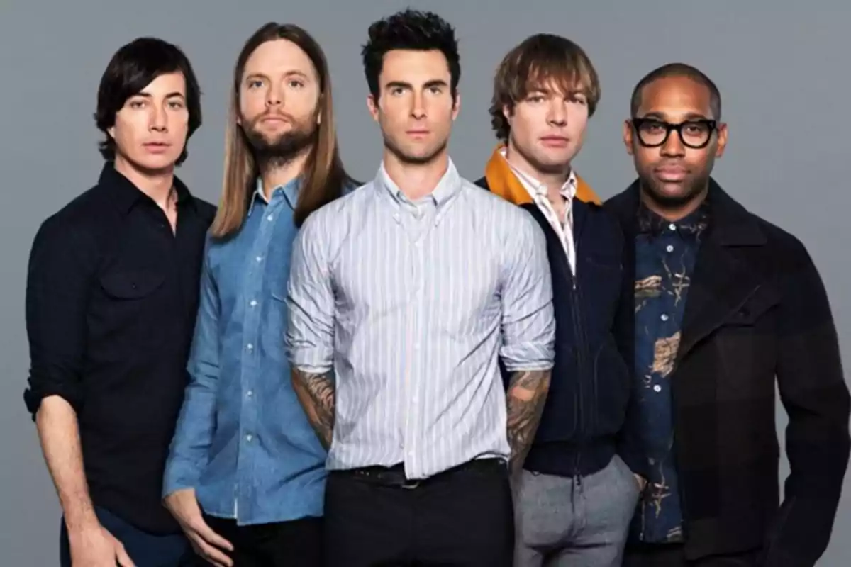 Five men pose together in front of a gray background, all dressed in casual clothing and looking at the camera.