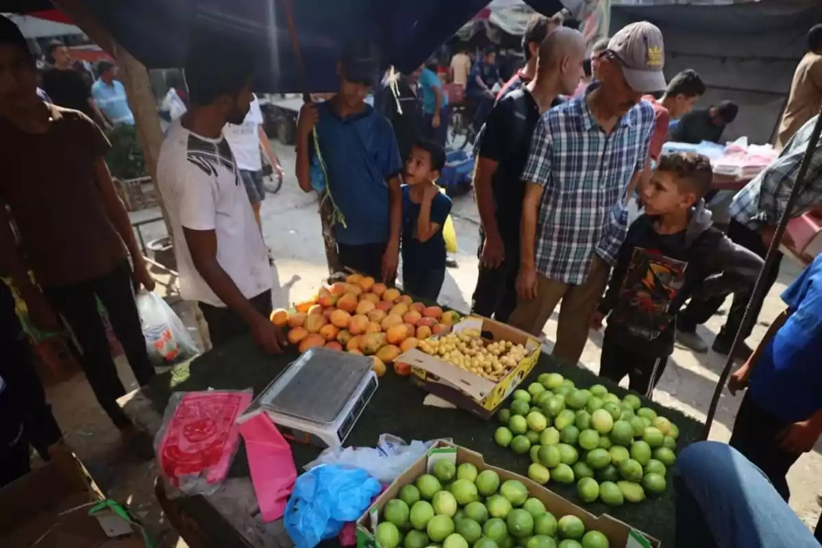 People gathered around a fruit stand at an outdoor market