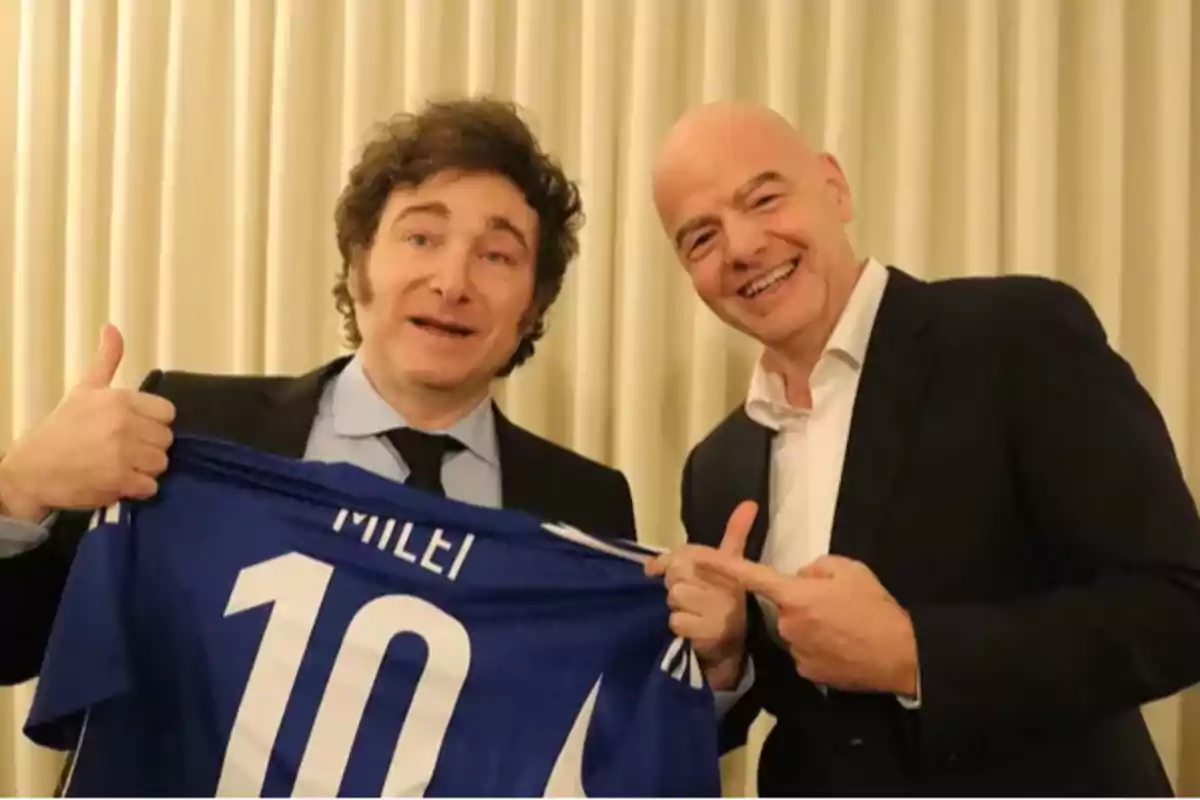 Two men smile while holding a blue soccer jersey with the number 10 and the name Milei.