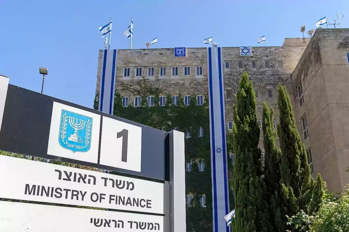 Building of the Israeli Ministry of Finance with Israeli flags on top and a sign in the foreground indicating the location Building of the Israeli Ministry of Finance with Israeli flags on top and a sign in the foreground indicating the location