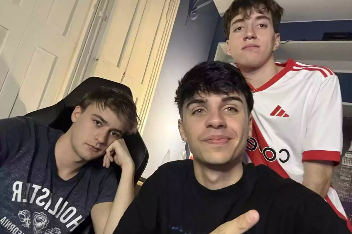 Three young people pose for a selfie in a room; one of them is wearing a white and red soccer jersey, and another is sitting in a gaming chair. Three young people pose for a selfie in a room; one of them is wearing a white and red soccer jersey, and another is sitting in a gaming chair.