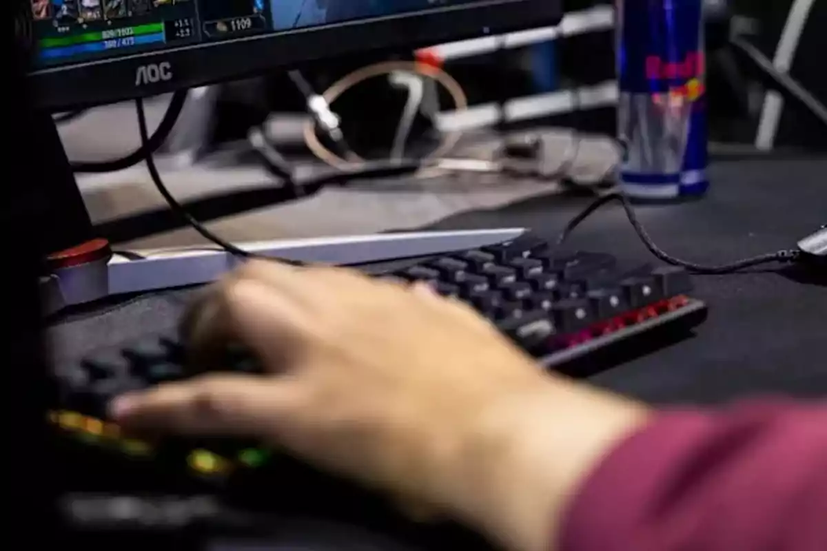 Person playing on a computer with a mechanical keyboard and an energy drink can on the desk Person playing on a computer with a mechanical keyboard and an energy drink can on the desk