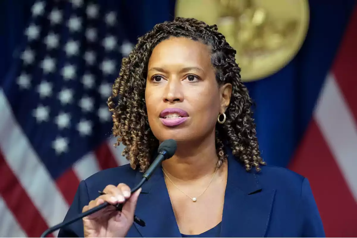 Mujer hablando frente a un micrófono con banderas de Estados Unidos de fondo Mujer hablando frente a un micrófono con banderas de Estados Unidos de fondo