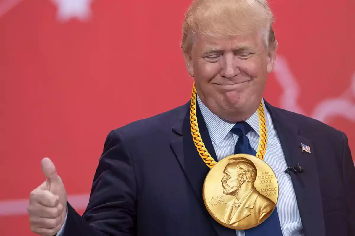 Man in a suit with a large gold medal hanging from his neck giving a thumbs-up in front of a red background