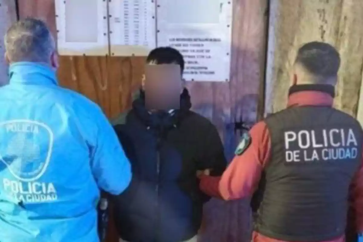Two city police officers detain a person in front of a wooden door. Two city police officers detain a person in front of a wooden door.