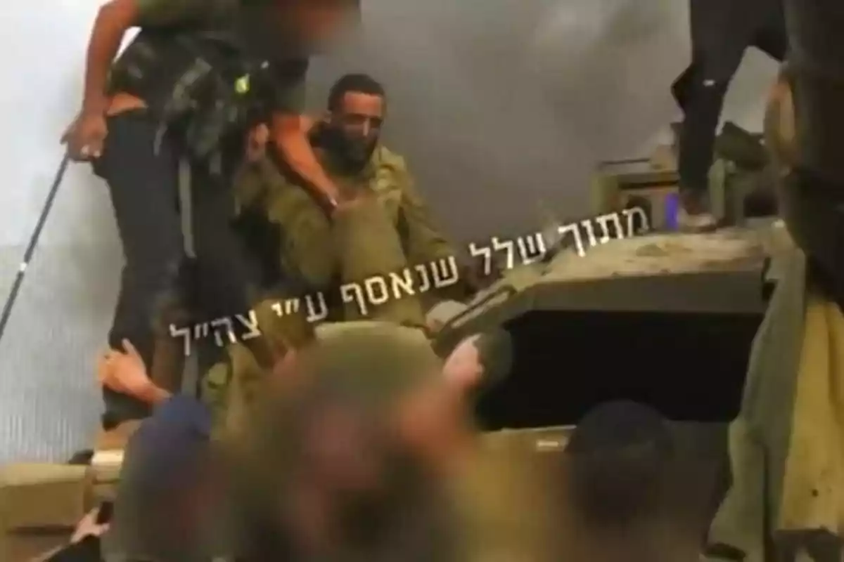Several soldiers in military uniforms are gathered around an armored vehicle while some of them help another soldier climb up.