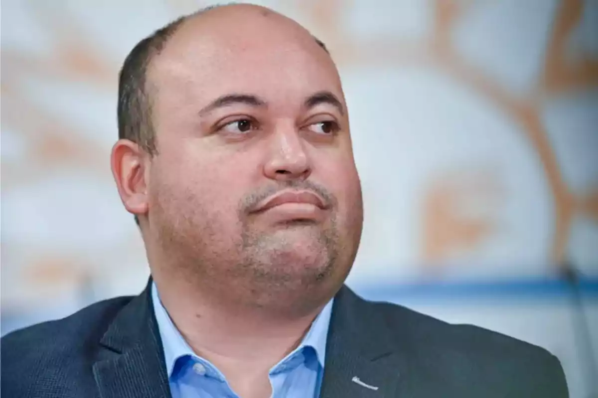 Hombre calvo con barba incipiente vistiendo saco azul y camisa celeste mirando hacia la derecha Hombre calvo con barba incipiente vistiendo saco azul y camisa celeste mirando hacia la derecha