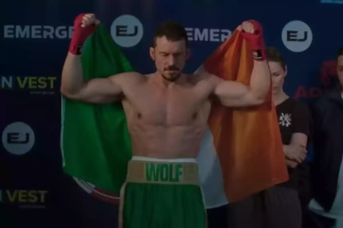 Boxeador con guantes rojos sosteniendo la bandera de Irlanda y usando pantalones cortos verdes con la palabra WOLF en la cintura Boxeador con guantes rojos sosteniendo la bandera de Irlanda y usando pantalones cortos verdes con la palabra WOLF en la cintura