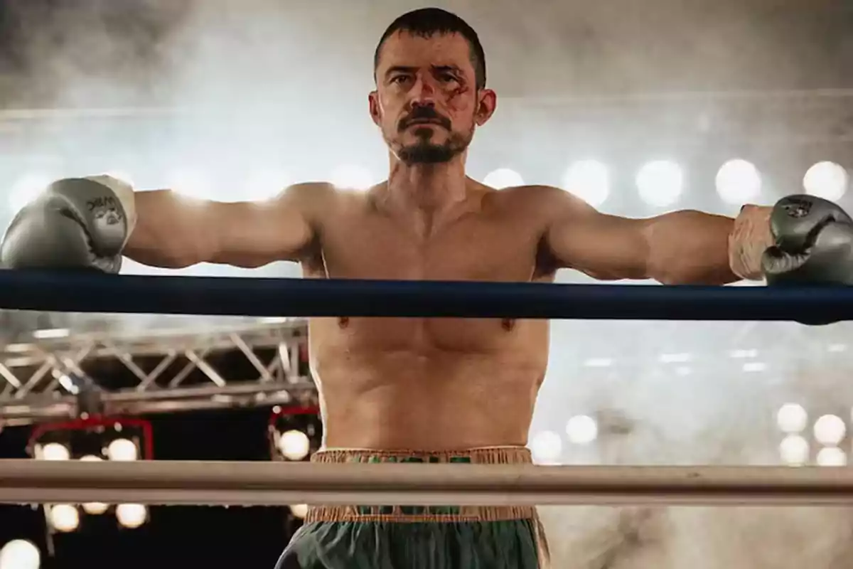 Boxeador con guantes y el rostro herido apoyado en las cuerdas del ring bajo luces brillantes Boxeador con guantes y el rostro herido apoyado en las cuerdas del ring bajo luces brillantes