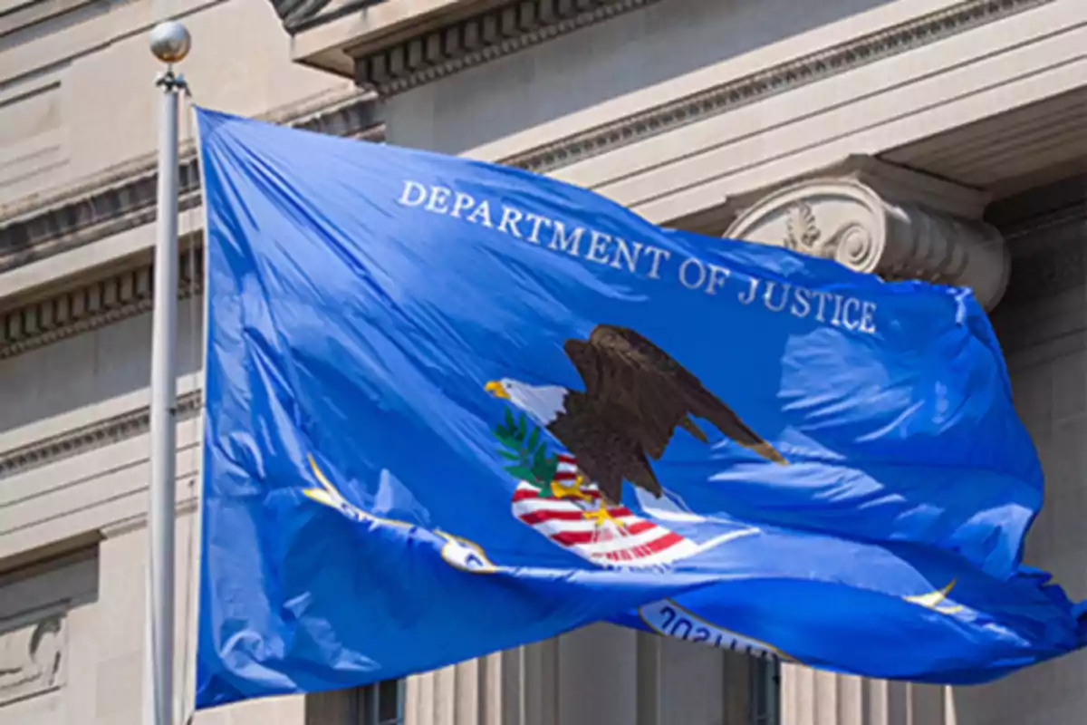 Bandera azul del Departamento de Justicia de Estados Unidos ondeando frente a un edificio oficial