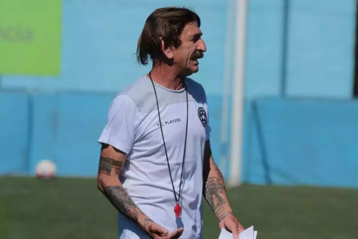 Man with tattoos and a whistle around his neck giving instructions on a soccer field Man with tattoos and a whistle around his neck giving instructions on a soccer field