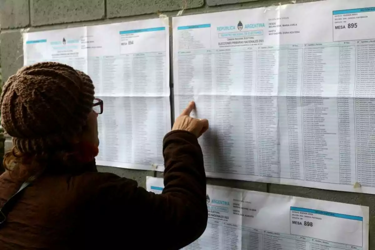 Person checking an electoral roll posted on a wall during an election day in Argentina.