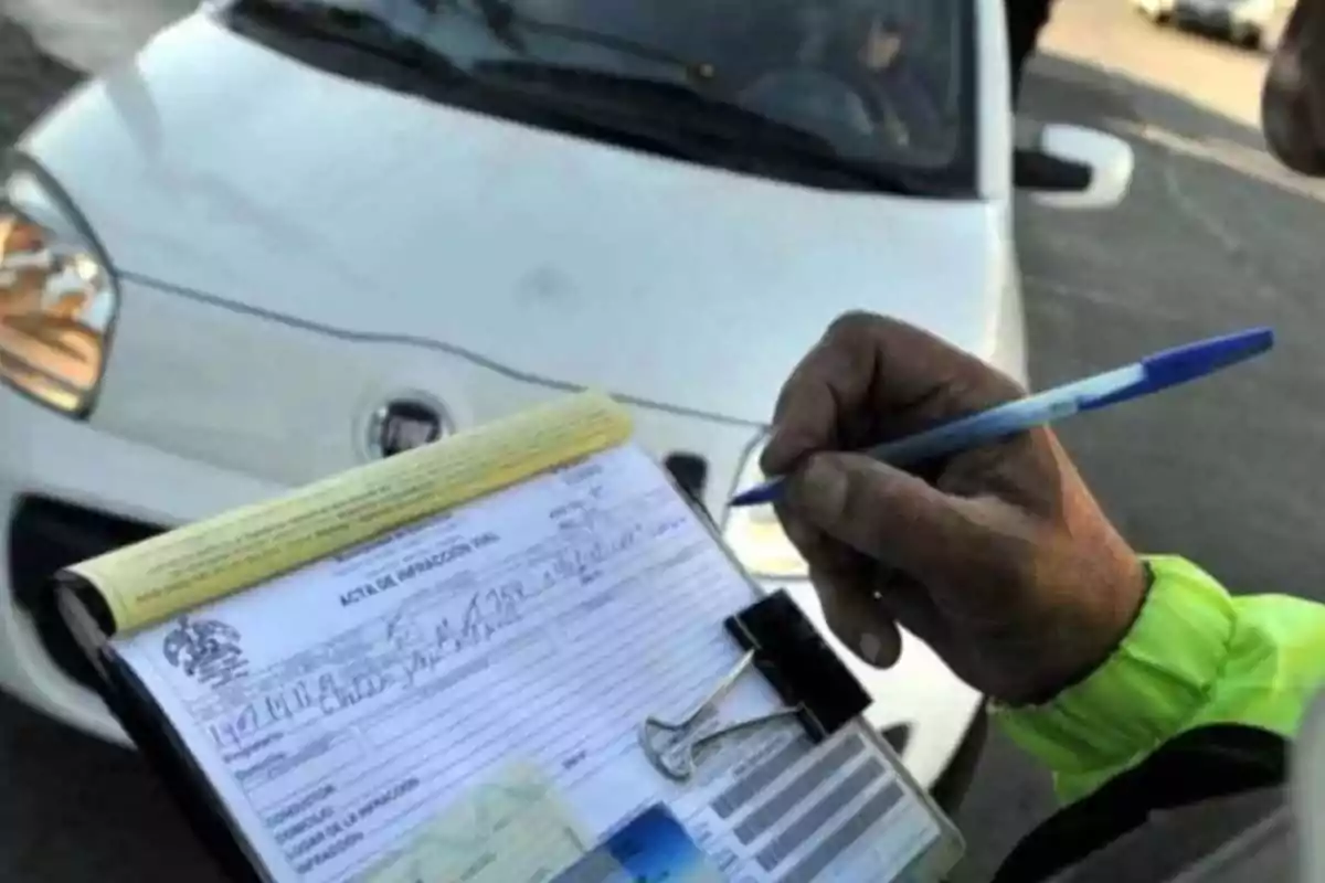 Persona llenando una multa de tránsito frente a un automóvil blanco Persona llenando una multa de tránsito frente a un automóvil blanco