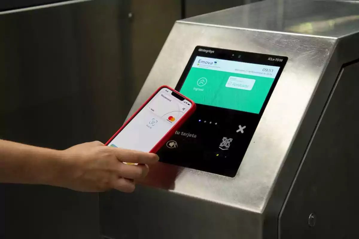 Persona usando su teléfono móvil para pagar en un lector digital de acceso al transporte público Persona usando su teléfono móvil para pagar en un lector digital de acceso al transporte público