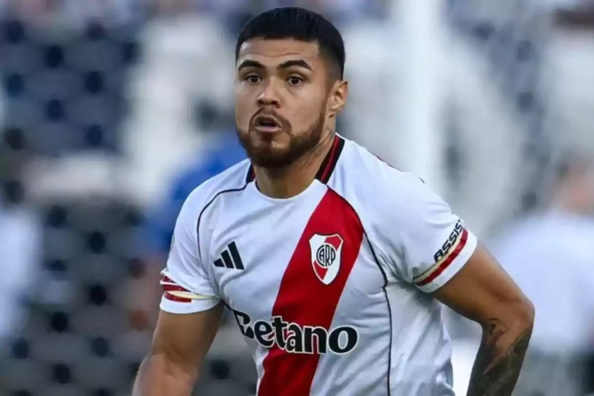 Futbolista con camiseta blanca de River Plate con banda roja en un partido