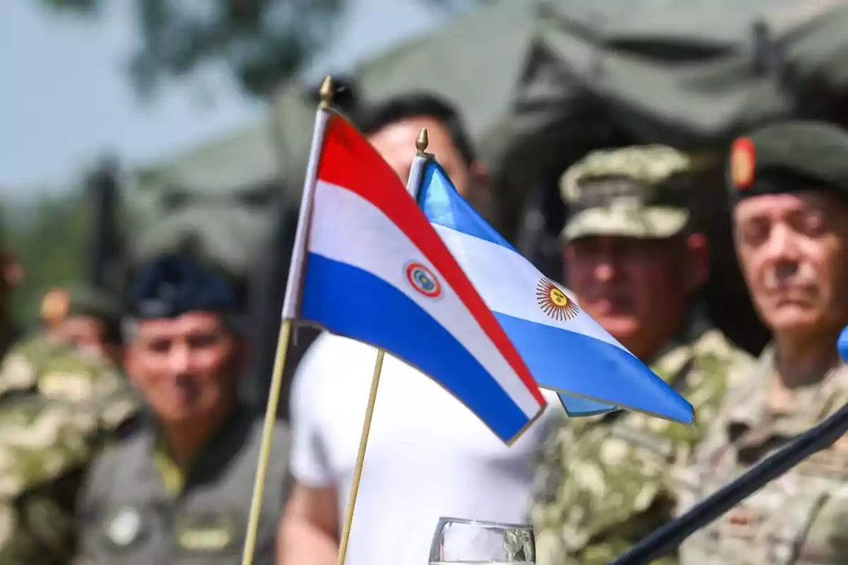 Paraguayan and Argentine flags in the foreground with blurred soldiers in the background