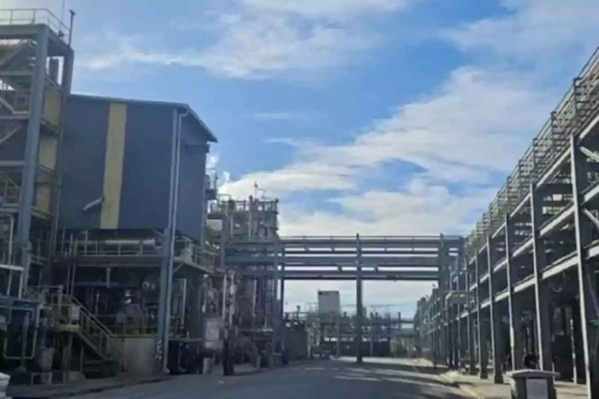 Vista de una planta industrial con estructuras metálicas y cielo parcialmente nublado