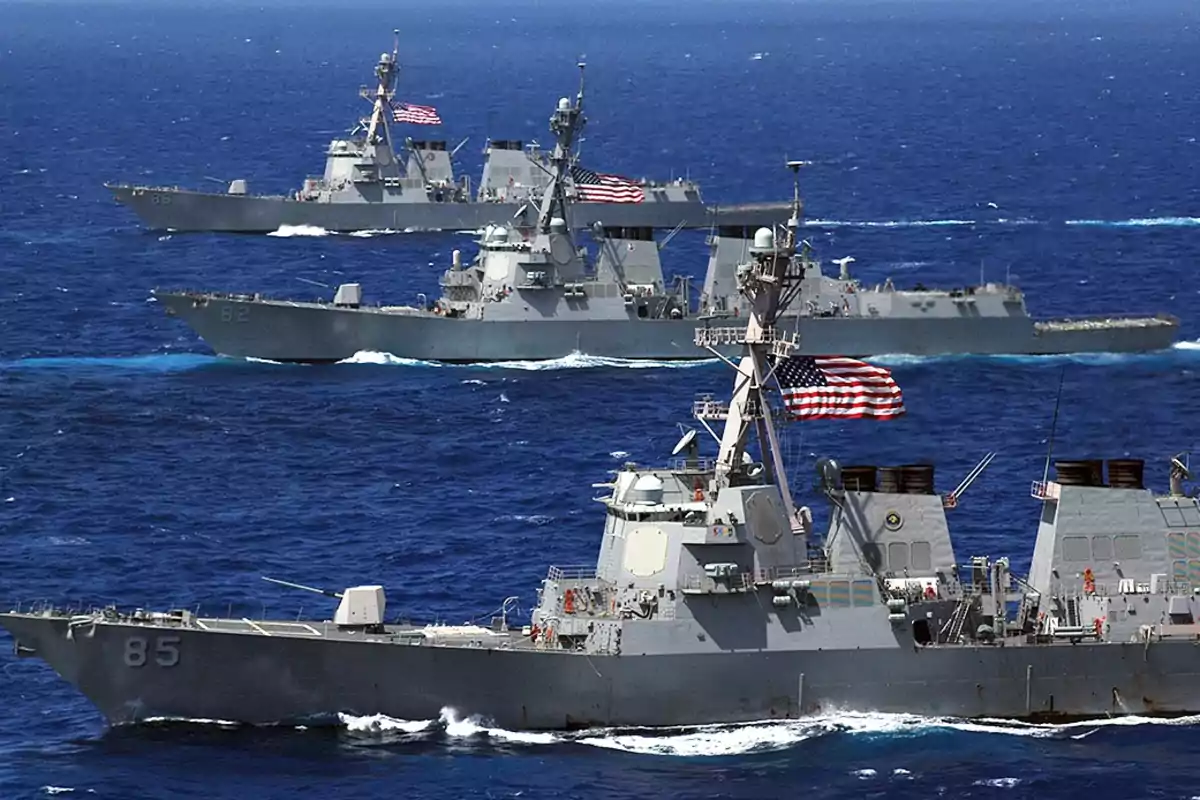 Tres buques de guerra navegando en formación sobre el mar con banderas de Estados Unidos ondeando