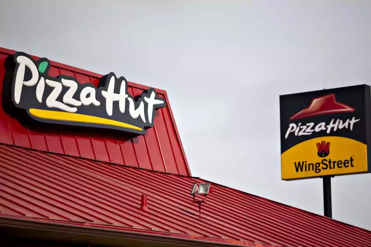 Fachada de un restaurante Pizza Hut con techo rojo y letrero de WingStreet al fondo