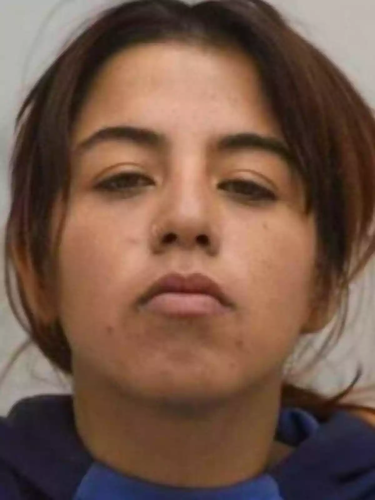 Young woman with brown hair and fair skin looking straight ahead with a serious expression