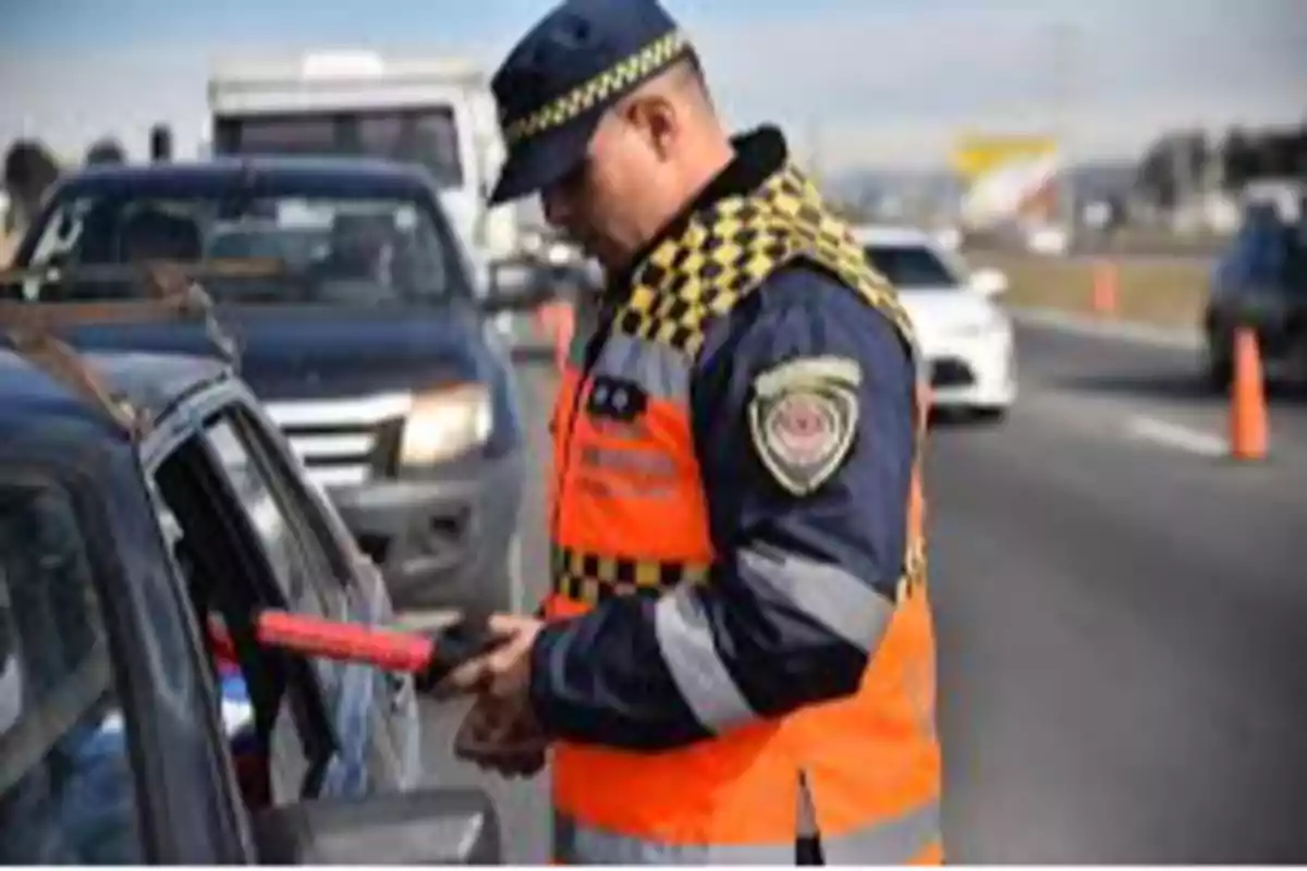Oficial de tránsito revisando documentos a un conductor en un retén vial sobre una carretera Oficial de tránsito revisando documentos a un conductor en un retén vial sobre una carretera