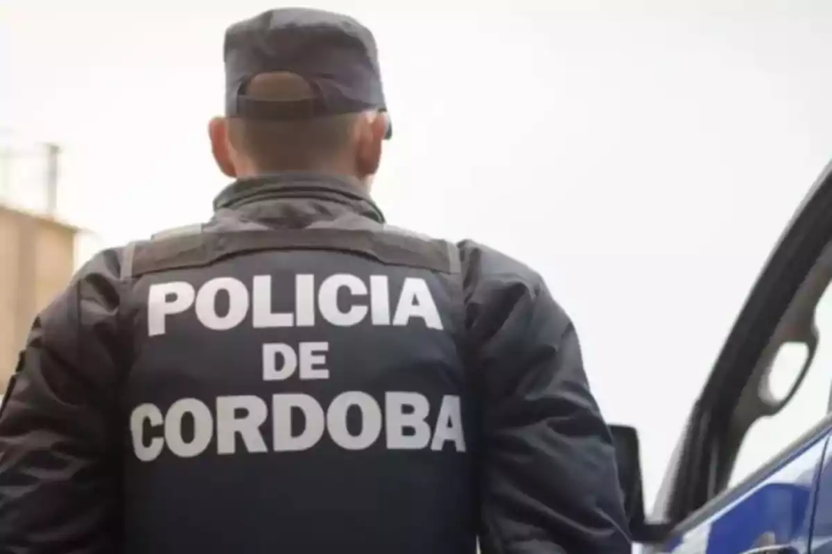 Un policía de Córdoba de espaldas junto a un vehículo patrulla